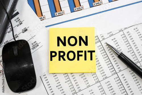 NON PROFIT text on stickers. Financial document with table and numbers. Pen and laptop. Business and accounting concept.