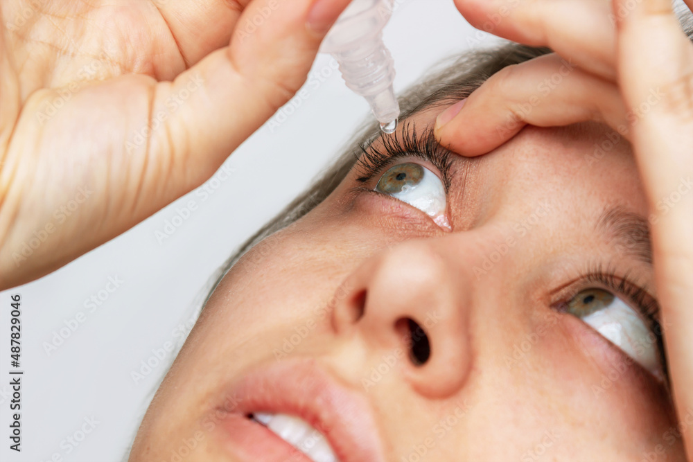 Closeup of woman dripping her eyes with medicinal drops natural tear