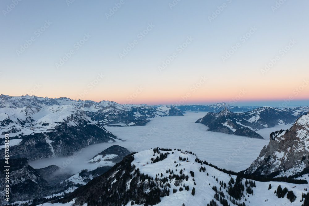 Amazing sunrise with red sky and a beautiful landscape in the wonderful region in Switzerland called Mythenregion. Beautiful mountain called Mythen and an epic sea of fog in the background.