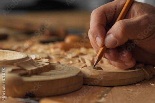 Woodworker's workbench. Close up of hands of senior carpenter doing some markings on wooden bar with pencil. Man working with woodcarving instruments