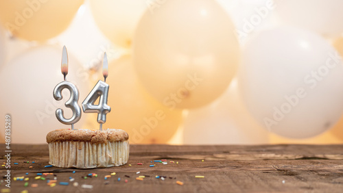 Happy birthday card with candle number 34 in a cupcake against the background of balloons. Copy space happy birthday for thirty three years old photo