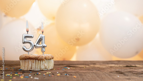 Happy birthday card with candle number 54 in a cupcake against the background of balloons. Copy space happy birthday for fifty four years old photo