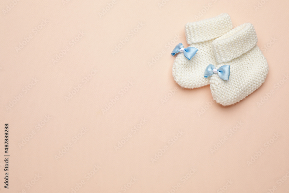 Knitted baby booties on light pink background, flat lay. space for text