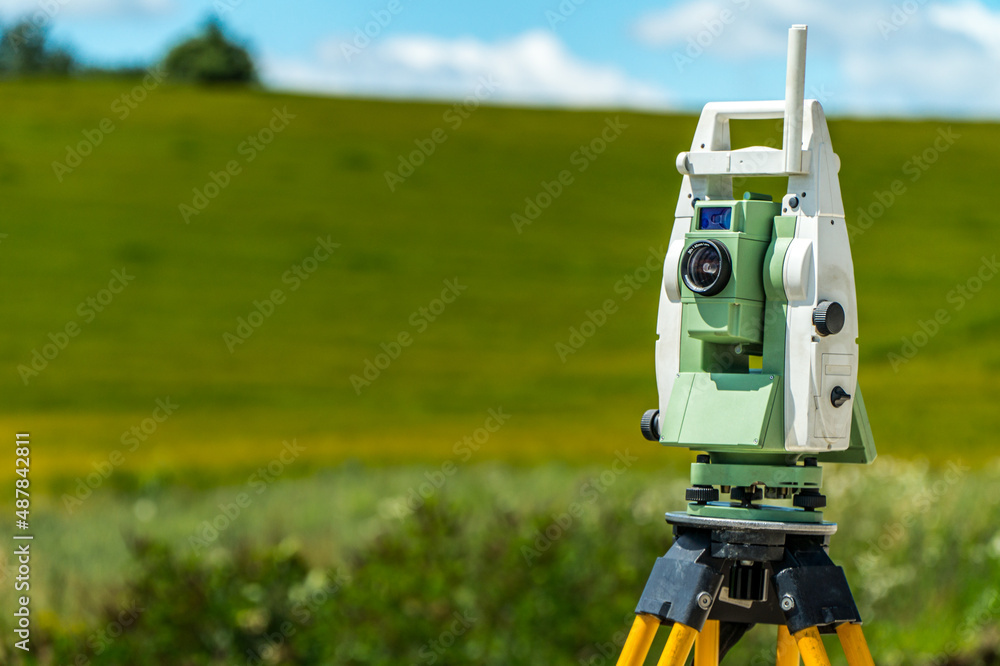 Surveyors equipment (theodolite or total positioning station) on the construction site of the road, highway or building with construction machinery background