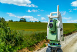 Surveyors equipment (theodolite or total positioning station) on the construction site of the road, highway or building with construction machinery background