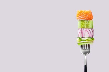 Close-up of fork with food on it: delicious fillet salmon, cucumber, onion, green salad on gray color background. Concept of healthy diet and clean eating with fish and vegetables, balanced nutrition