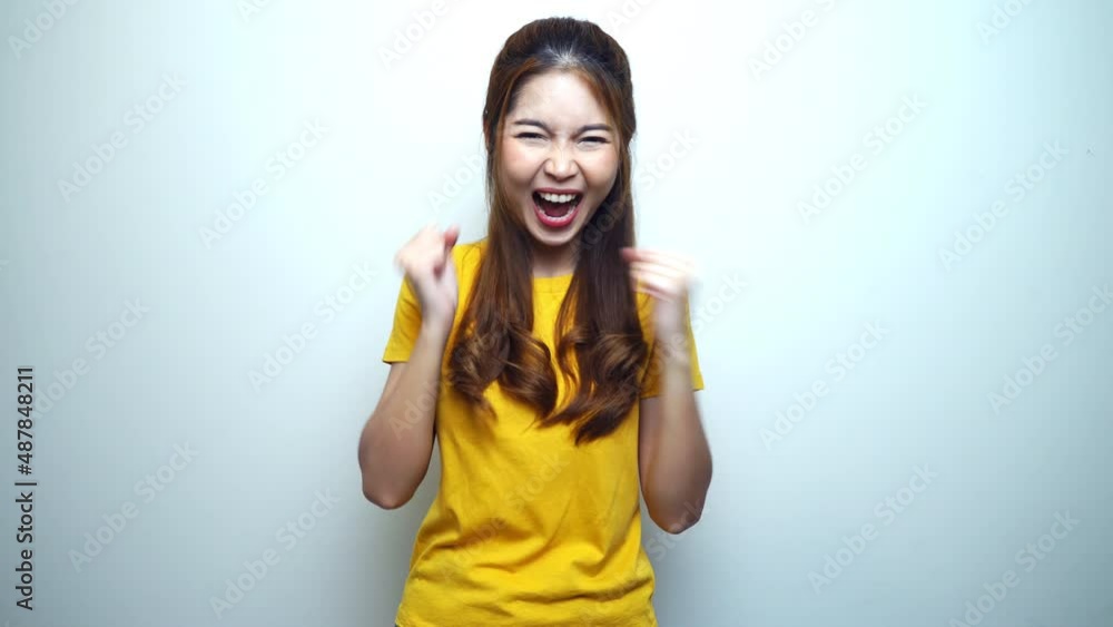 Happy young Asian woman celebrating with fist pump and smiling, white background. Happy young Asian woman celebrating with fist pump and smiling, white background.