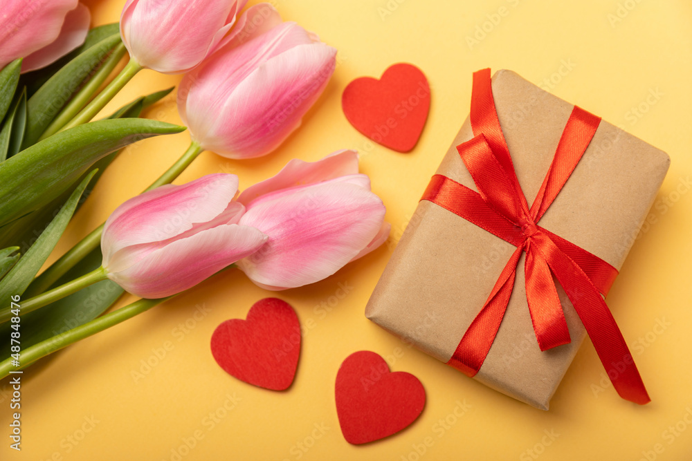 Pink tulips and a gift box on a yellow background.Top view. Spring bouquet.Holiday concept.Women's day, Valentine's day,Easter, birthday.Copy space. Pink tulips and a gift box on a yellow background.Top view. Spring bouquet.Holiday concept.Women's day, Valentine's day,Easter, birthday.Copy space.