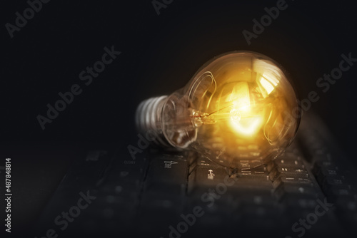 Light bulb glowing on pc keyboard, idea of business ​​inspiration, innovation idea concept.