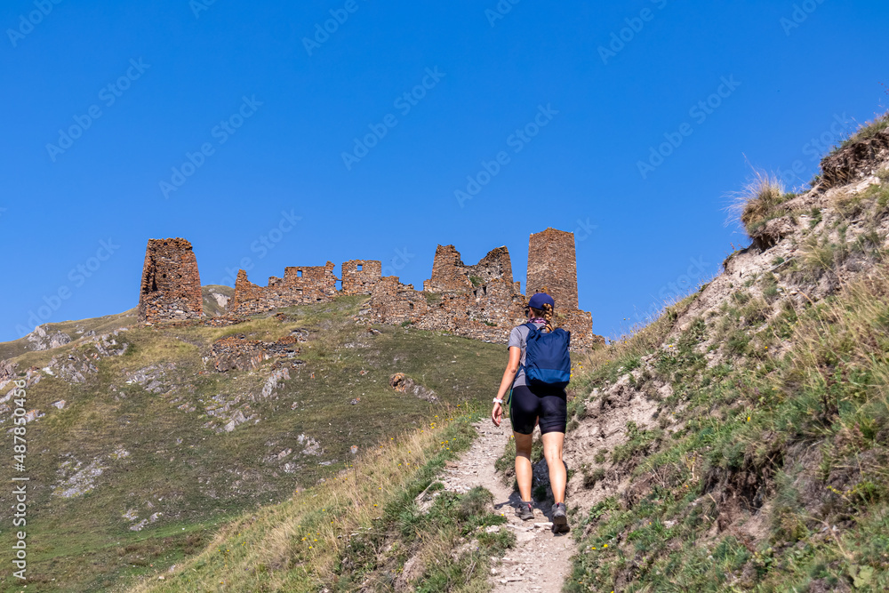 A woman on a hiking trail leading to the ruins of the Zakagori fortress in the Truso Valley near the Ketrisi Village Kazbegi District, Mtskheta-Mtianet in the Greater Caucasus Mountains, Georgia.