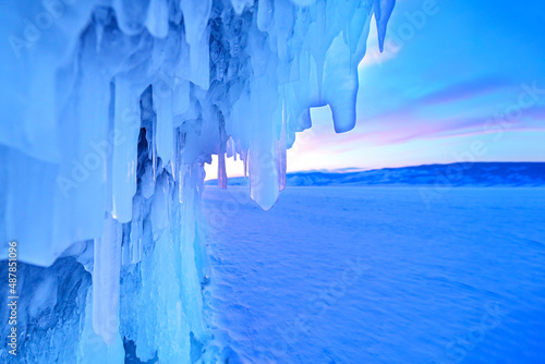 Ice cave on Baikal lake in winter. Blue ice and icicles in the sunset sunlight. Olkhon island, Baikal, Siberia, Russia. Beautiful winter landscape. © Людмила Колядицкая