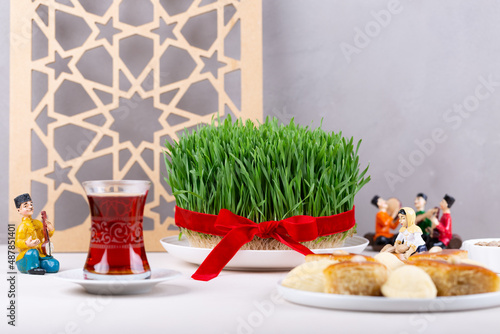 Green fresh semeni sabzi wheat grass in white plate with traditional Azerbaijani pastry shekerbura and pakhlava with wooden shebeke pattern, Novruz spring equinox celebration in Azerbaijan photo