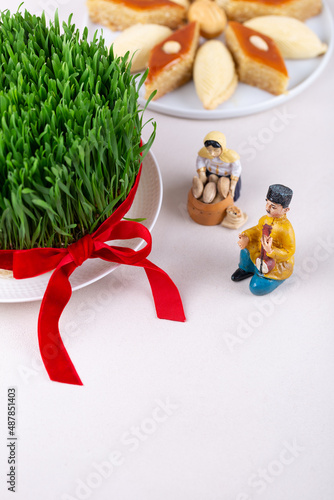 Green fresh semeni sabzi wheat grass in white plate with traditional Azerbaijani pastry shekerbura and pakhlava with wooden shebeke pattern, Novruz spring equinox celebration in Azerbaijan