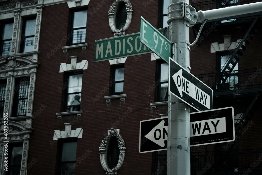Obraz premium One way direction signs in Madison street with the 97 street in New York. New York stile building at the background.