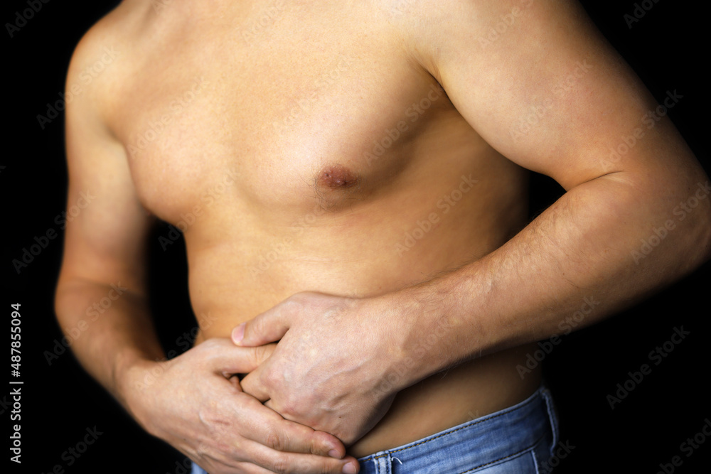 Muscular man suffering from abdomen pain, male torso on black background. Stomach diseases or pancreas inflammation Muscular man suffering from abdomen pain, male torso on black background. Stomach diseases or pancreas inflammation