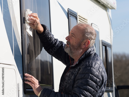 Fotografiet A bearded male motorhome owner cleans his recreational vehicle window