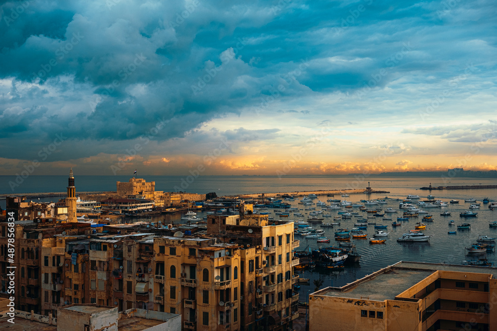 View of the Alexandria port at sunrise, golden blue sky. Amazing view of hundreds of little fishing boats anchored in the ancient harbour, citadel seen in the distance