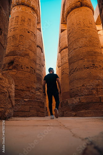 Vertical shot of man tourist walking around the massive pillars in luxor temple in egypt. Ancient egyptian pillars stand here after thousands of years, available for people to visit