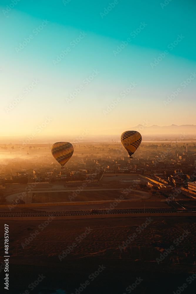 Luxor Egypt January 2021 Vertical shot of two hot air balloons in luxor, egypt. Amazing early morning sunrise illuminated over the amazing foggy landscape