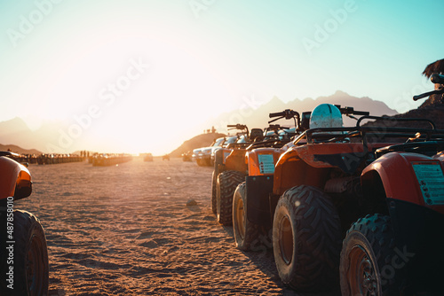 View of several atv quad bikes parked inline in the middle of a desert near hurghada. Sunset hour with the sun shining straight at the camera