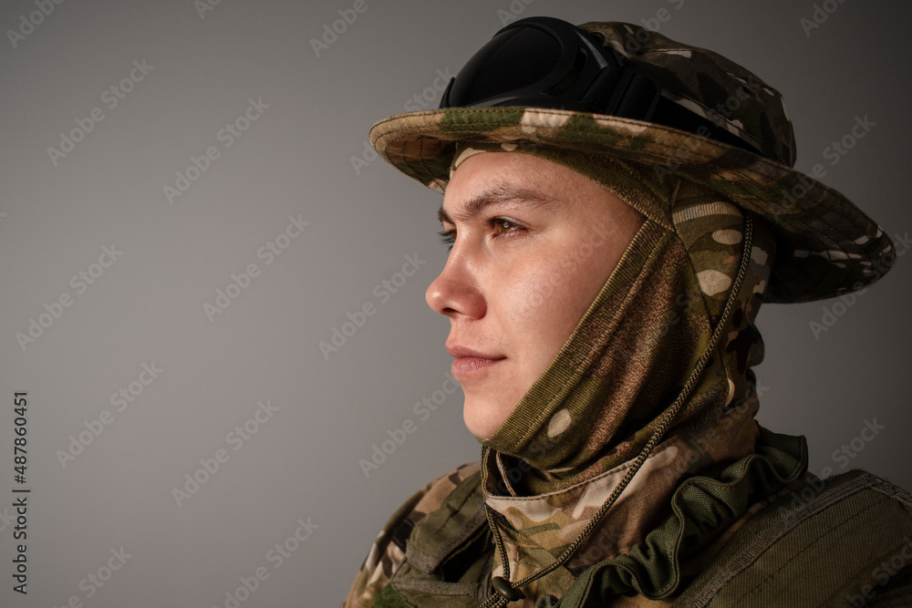 A close-up shot of a military man in a uniform in a hat with goggles giving orders on the grey background. Portrait of the soldier . Calm warrior. Army. Commando. Call of duty. A close-up shot of a military man in a uniform in a hat with goggles giving orders on the grey background. Portrait of the soldier . Calm warrior. Army. Commando. Call of duty.