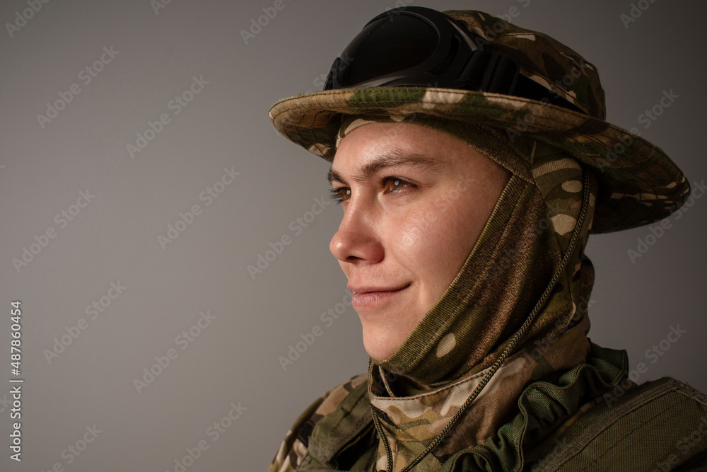 A close-up shot of a military man in a uniform in a hat with goggles giving orders on the grey background. Portrait of the soldier . Calm warrior. Army. Commando. Call of duty. A close-up shot of a military man in a uniform in a hat with goggles giving orders on the grey background. Portrait of the soldier . Calm warrior. Army. Commando. Call of duty.