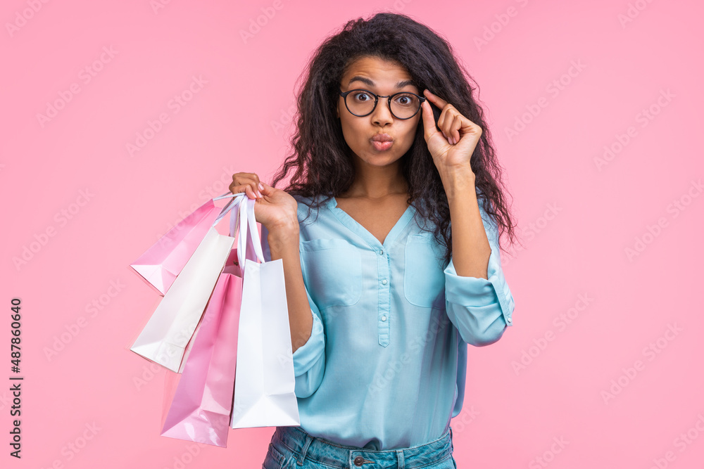 Studio portrait of cute coquette trendy young woman wearing fashionable eyeglasses, posing over pastel pink background Studio portrait of cute coquette trendy young woman wearing fashionable eyeglasses, posing over pastel pink background