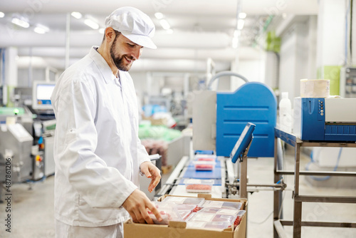 Fotografie A meat factory worker packing fresh meat into boxes and preparing it for transport