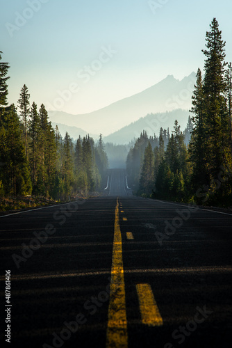Scenic roadway view with foggy mountains and smoke in the sky