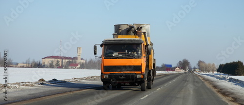 Yellow loaded mini truck on empty countruside winter road in Europe. Front view. Transportation logistics. photo
