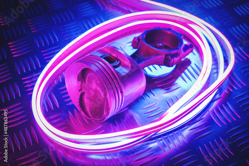 Car engine piston in the neon lights close up background.