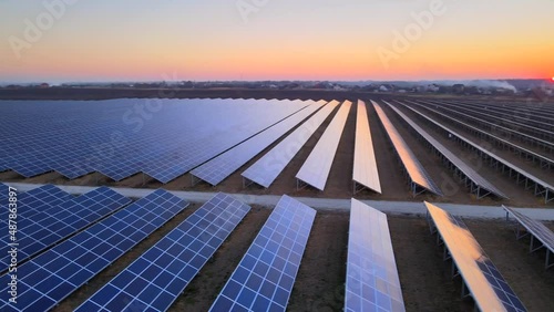Aerial drone view of large solar panels at a solar farm at bright sunset in early winter. Solar cell power plants