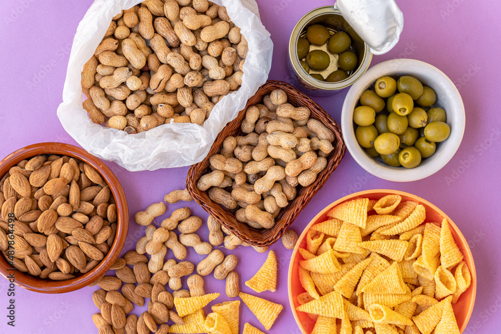 Top view of an assortment of appetizers, with peanuts, almonds, anchovy stuffed olives and baked corn snacks. Snack concept.