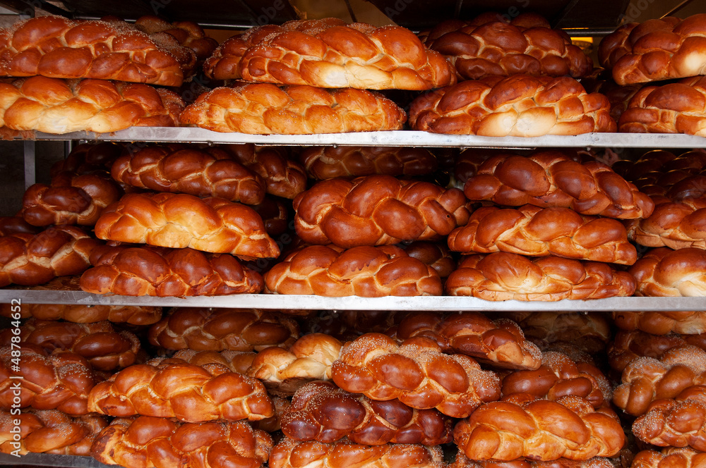 Loaves of freshly baked, braided, challah egg bread rest on display racks outside a bakery on a Jerusalem street on the eve of the Jewish sabbath.