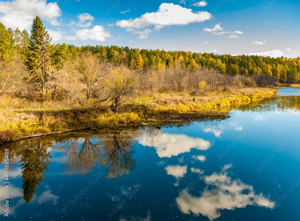 Autumn landscape with river, trees, grass and blue sky