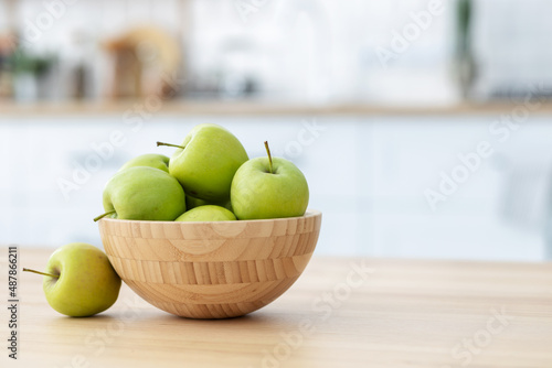 Fresh green apples in a wooden bowl on a wooden table witj copy space. Healthy eating photo