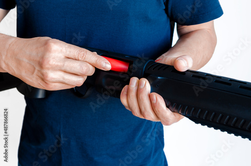 The man charges the shotgun with ammunition. Charging a pump smoothbore weapon