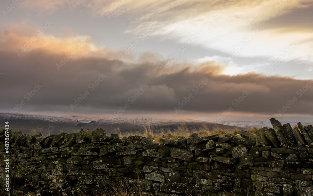 A dry stone wall with snow covered hills beyond in Weardale, the North Pennines, County Durham, UK