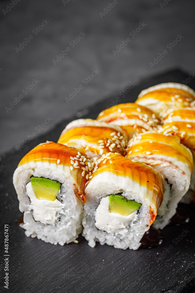 appetizing Philadelphia sushi roll with eel and avocado on a black stone plate appetizing Philadelphia sushi roll with eel and avocado on a black stone plate