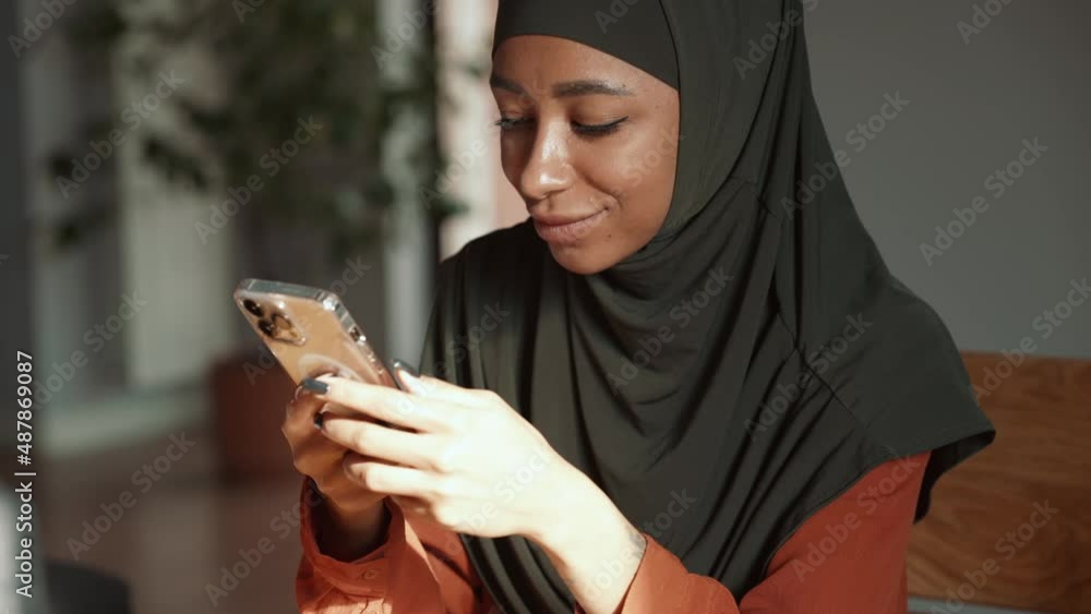 Pensive Muslim woman texting by phone at home Pensive Muslim woman texting by phone at home