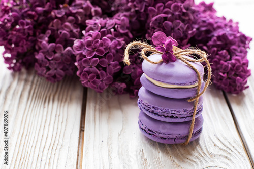 purple macaroons and lilacs on a white wooden background. place for text