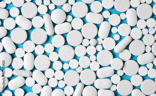 many white pills on a blue background. Top view