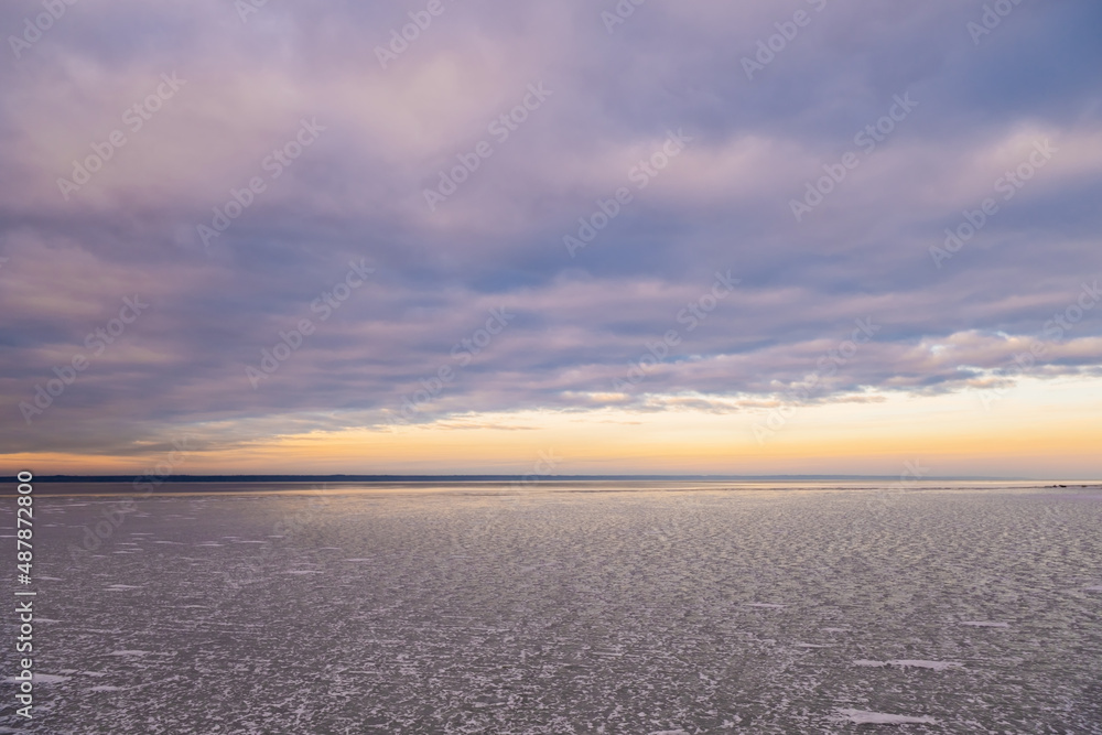 Fototapeta premium Heavy, dramatic sky over a frozen river. Frozen river at sunset.