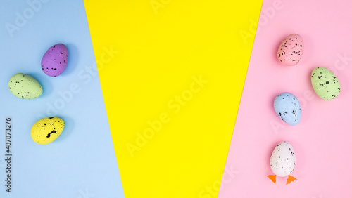 Easter flat lay arrangement with eggs on vibrant pastel blue yellow and pink bakcgorund.  Spring holidays concept. MInimal copy space photo