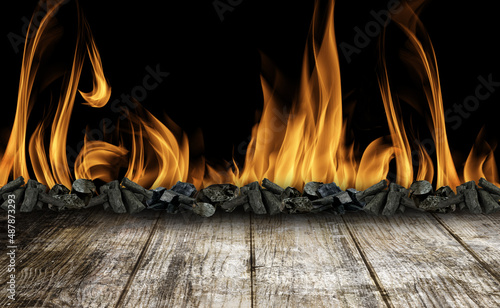 Mesa de madeira envelhecida , no fundo carvão com fogo e fumaça. Fundo ideal para produção com churrasco. photo