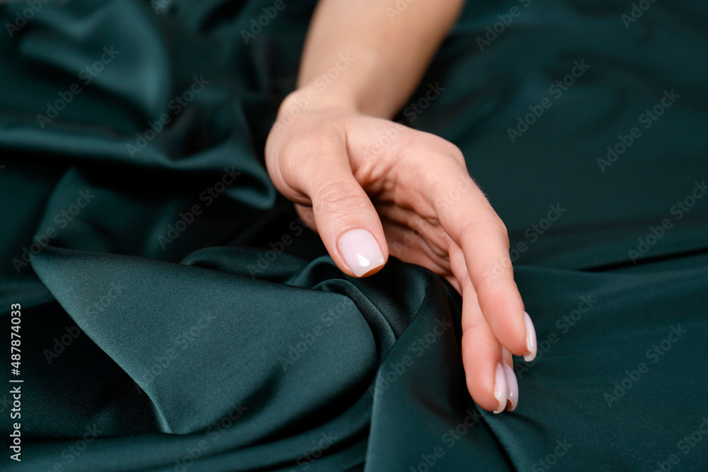 Woman touching soft dark green fabric, closeup Woman touching soft dark green fabric, closeup