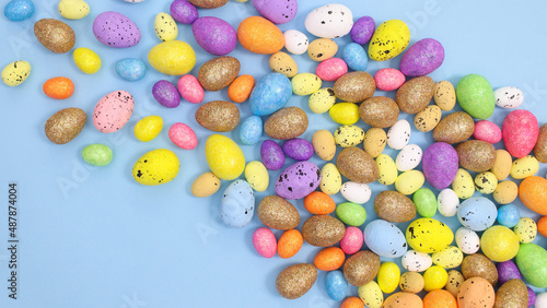 Pile of colorful eggs for Easter on bright pastel blue background. Flat lay creative arrangement. Spring holidays aesthetic