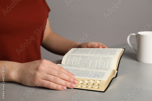 Woman reading Bible at light table, closeup