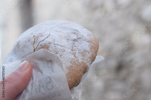 Ericino, a type of traditional dessert from Erice (Sicily) with icing sugar filled with lemon cream, held in the hand 
