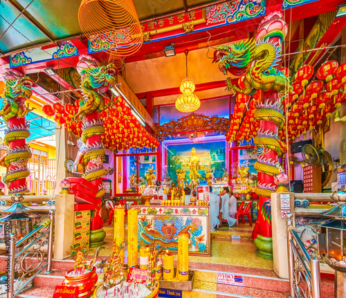 The bright interior of Guan Yin Shrine of Wat Kanma Tuyamaram with colorful pillars in form of dragons, photo